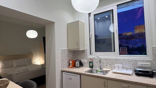 Een moderne keuken met een inbouwvaatwasser, een raam met uitzicht op een historisch pand, en een eethoek met een tafel en stoelen.