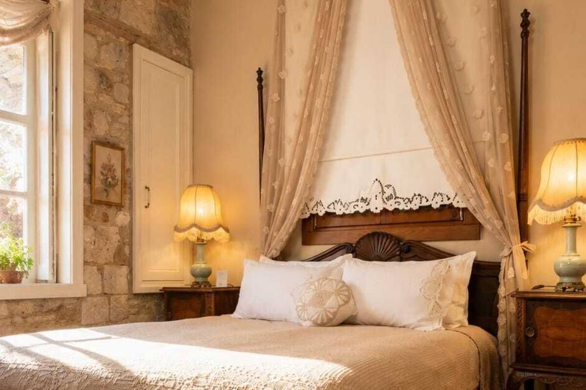 Un dormitorio con cama de dosel, pared de piedra, ventana con vistas y mesita de noche con lámpara.