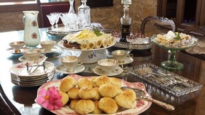 Une table dressée avec différents plats, notamment une assiette de biscuits, un gâteau et plusieurs verres et tasses.