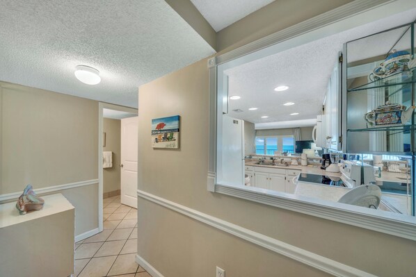 A modern kitchen with white cabinetry, a large window, and a decorative glass cabinet. - FREE Golf & Perks! Beachfront Mariner West 608 Swimming Pool, Tennis & Grills (Panama City Beach)