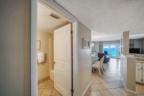 A modern kitchen with a dining area, a large window with a view, and a door leading to another room.