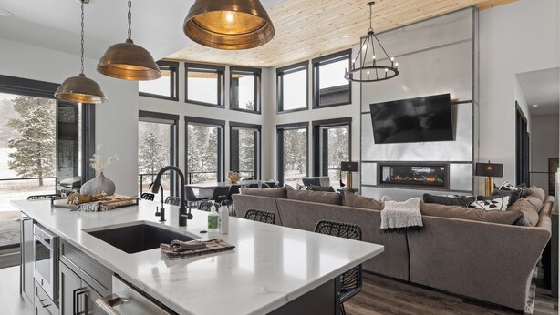 Eine moderne Küche mit einer großen Kochinsel, einem eingebauten Backofen und einem Essbereich mit einer Couch und Stühlen.