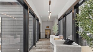 Ein modernes Interieur mit einer langen Diele, großen Fenstern und einer Sitzecke mit einer Pflanze.