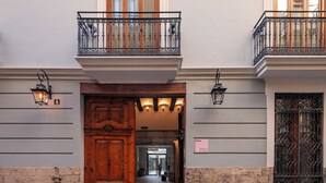 Un edificio con una puerta de madera grande, un balcón con barandillas de metal ornamentadas y un letrero que indica el nombre 'Numa Valencia La Xerea'.