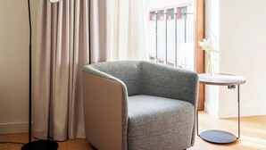 Una habitación moderna con un sillón gris, una lámpara de pie y una mesita con un florero.