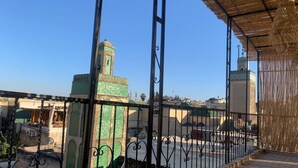 Un balcon avec vue sur un immeuble doté d’une tour verte et d’une tour plus petite en arrière-plan.