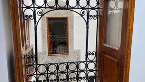 Une porte en bois avec un portail en métal, une fenêtre ornée de barreaux en fer et un mur à motifs.