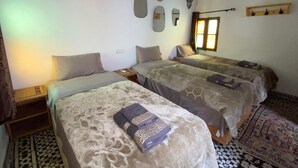 Une chambre d’hôtel avec deux lits, une fenêtre avec des rideaux et un tapis à motifs.