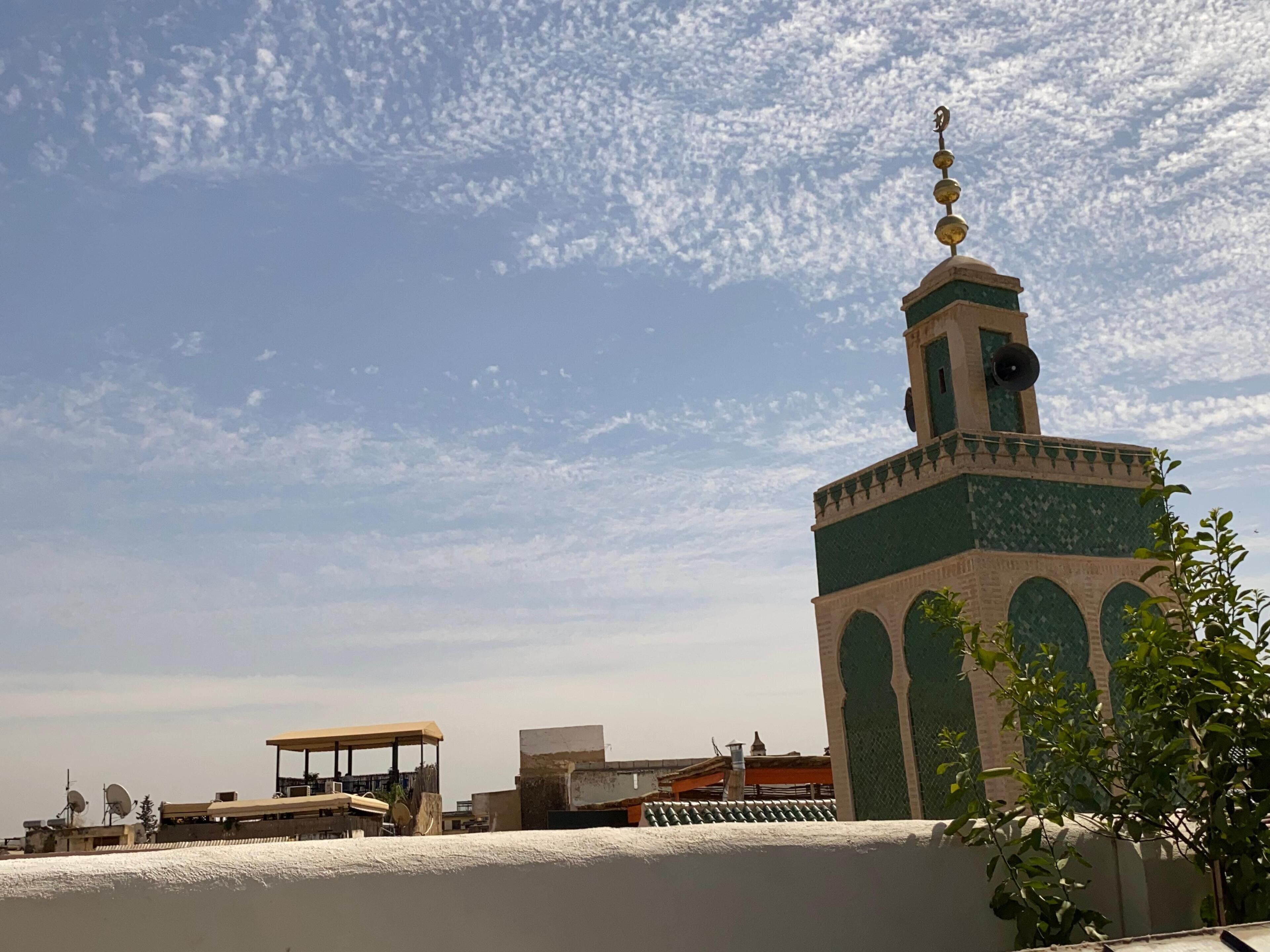 Eine Moschee mit einem Minarett, einem überdachten Außenbereich und Blick zum Himmel.