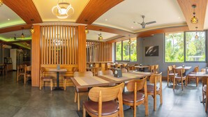 Un restaurant spacieux, doté de meubles en bois, de grandes fenêtres et d’un ventilateur de plafond.