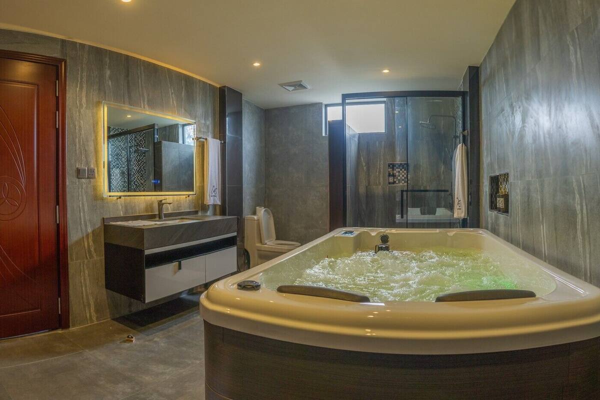 A modern bathroom with a large bathtub, a vanity with a mirror, and a shower area.