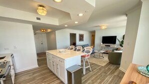 A modern kitchen with a central island, white cabinetry, and a stainless steel sink. - 1703 Brighton, newly remodeled condo with full access! (Myrtle Beach)