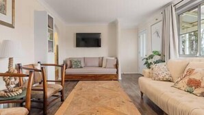 A living room with a sofa, a coffee table, and a TV mounted on the wall. - Cooinda, A 3 bedroom home near Mayfield Gardens (Oberon)