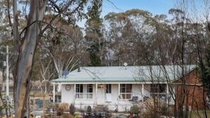 A white house with a green roof, surrounded by trees and a grassy yard. - Cooinda, A 3 bedroom home near Mayfield Gardens (Oberon)