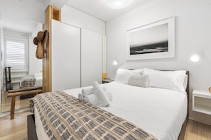 A neatly arranged bedroom with a bed, bedside tables, a bench, a wardrobe, and a framed picture on the wall. - Bay View in Rushcutters Bay (Rushcutters Bay)