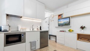A modern kitchen with built-in appliances, a clock, and a TV on the wall. - Bay View in Rushcutters Bay (Rushcutters Bay)
