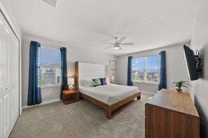 Spacious king bedroom with vibrant decor and a TV – your private sanctuary for rest and entertainment. - Resort Access: 6BR Home w Pool near Disney (Kissimmee)