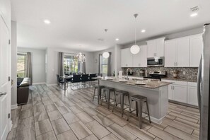 A modern kitchen with a central island, bar stools, and a dining area with a view.