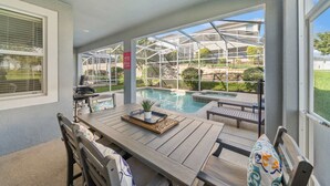 A covered patio area with a pool, seating, and a grill. - Disney Escape: Private Pool and Spa, Near Disney World ! (Kissimmee)