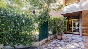 L’entrée d’un hôtel avec un patio carrelé, un portail vert et des plantes en pot.