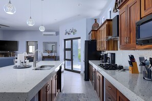 A modern kitchen with granite countertops, wooden cabinets, a built-in oven, and a large island with a sink.