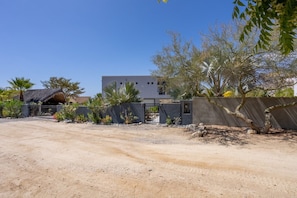 A desert landscape with a building, a thatched-roof structure, and a gate. - Sunny Poolside Escape Near the Beach (Los Barriles)