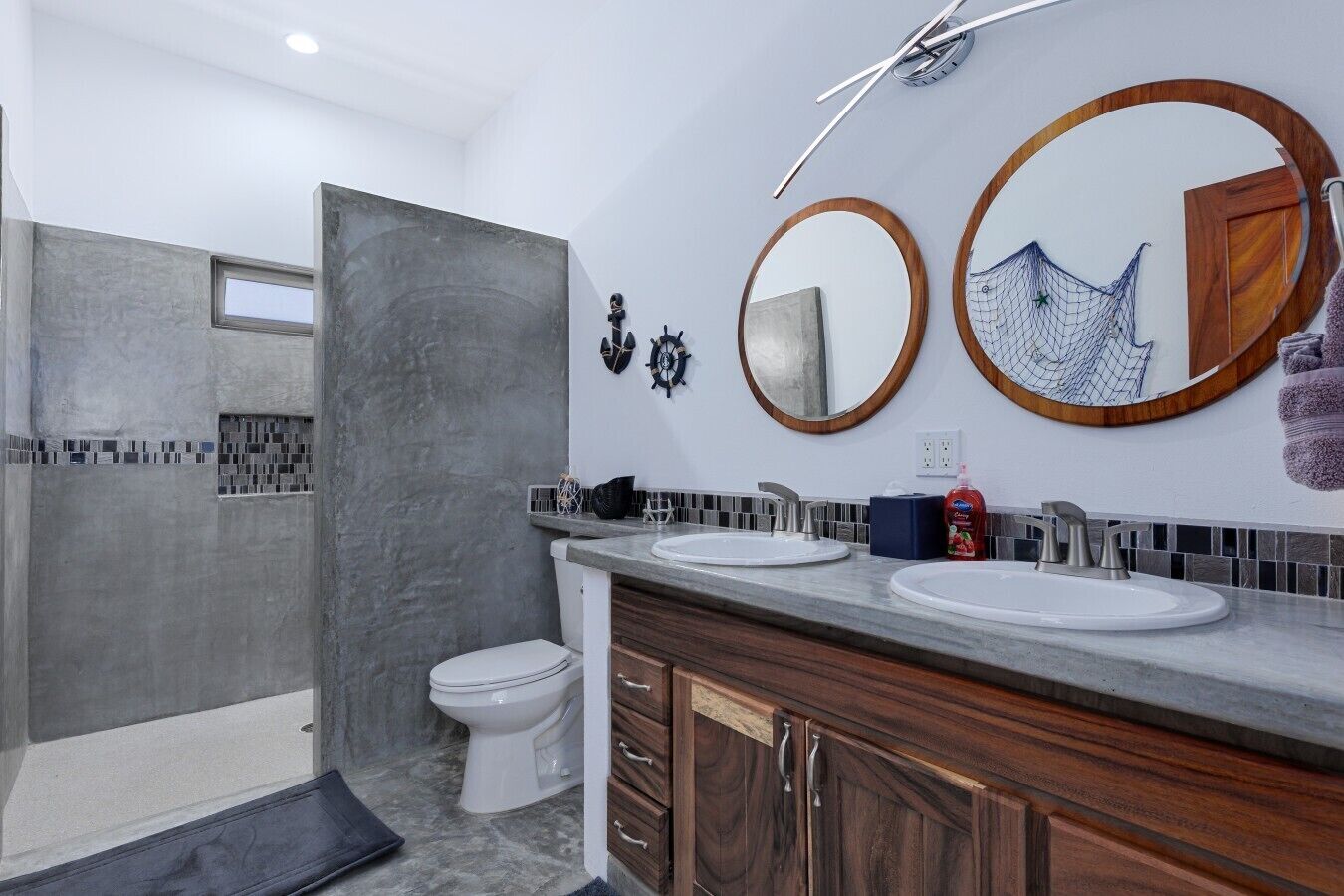 A modern bathroom with two sinks, a toilet, and a shower area.