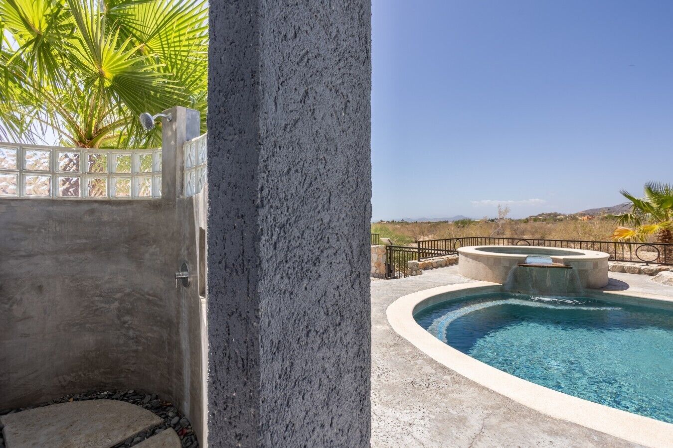 Zona de piscina con un jacuzzi, vistas del paisaje y una estructura de concreto.