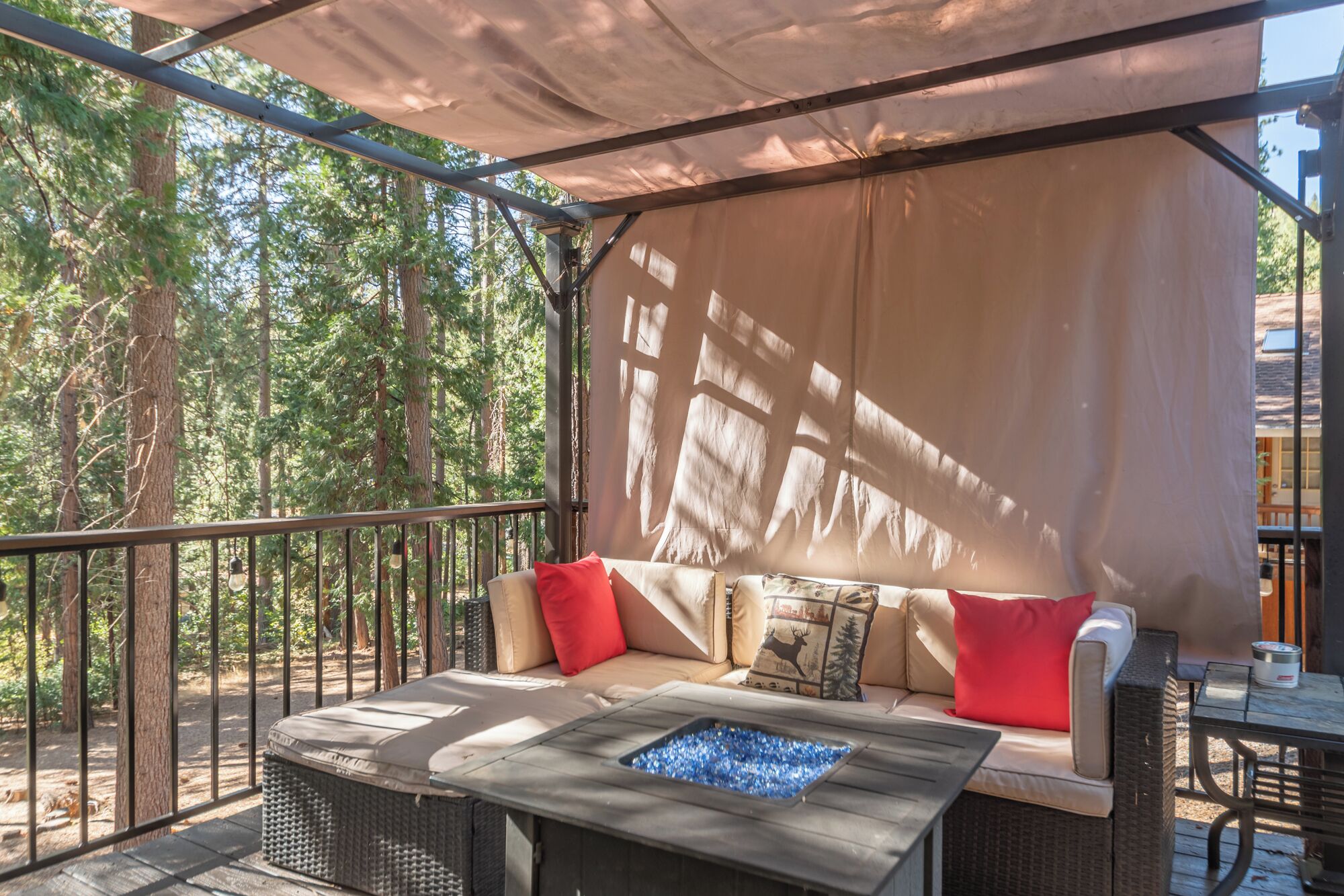 An outdoor seating area with a fire feature, a covered patio, and a view of the forest.