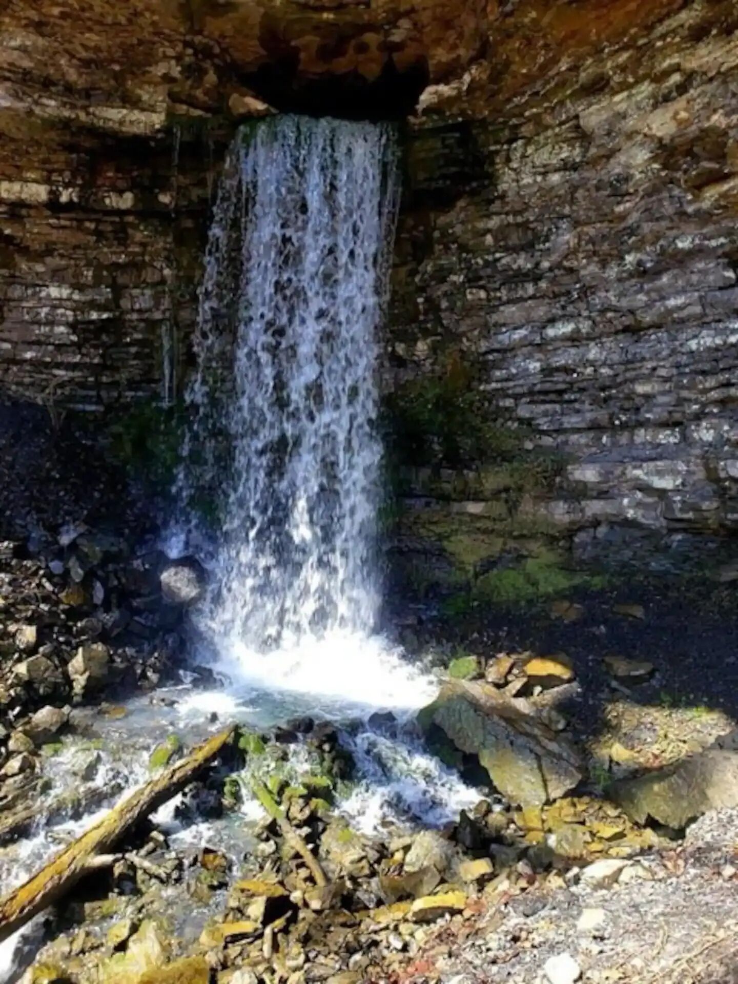 A waterfall in a rocky cave with water flowing down the center.