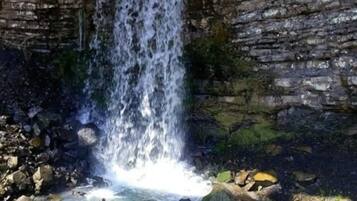 A waterfall in a rocky cave with water flowing down the center.