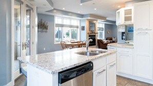 A modern kitchen with granite countertops, white cabinetry, and a dishwasher. - Stunning Downtown Condo w/ Water Views (Grand Haven)
