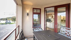 A balcony with a table and chairs, a view of the street, and a glimpse of the interior including a kitchen. - Stunning Downtown Condo w/ Water Views (Grand Haven)