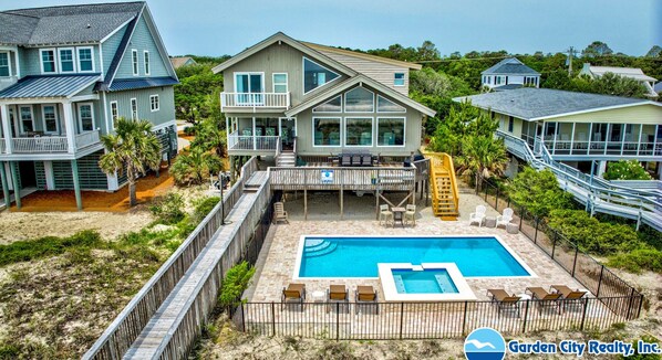 A residential property with a large backyard, a swimming pool, and a covered patio area.