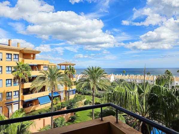 A hotel with multiple floors, balconies, and a view of the sea.