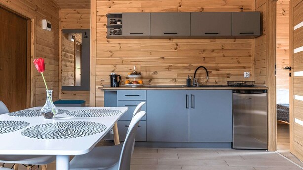 A modern kitchen with grey cabinets, a stainless steel refrigerator, and a wooden ceiling. - Cottage in Duszniki Zdrój with Spa Access (Duszniki Zdrój)