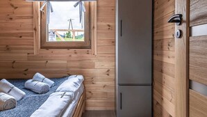 A wooden cabin room with a bed, a window, and a door. - Cottage in Duszniki Zdrój with Spa Access (Duszniki Zdrój)