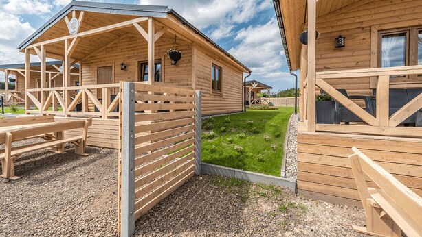 Une cabane en bois dotée d’un porche abrité et d’un petit jardin.