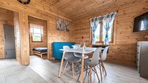 L’intérieur d’un chalet en bois comprend une table à manger, des chaises, un canapé et un coin cuisine.