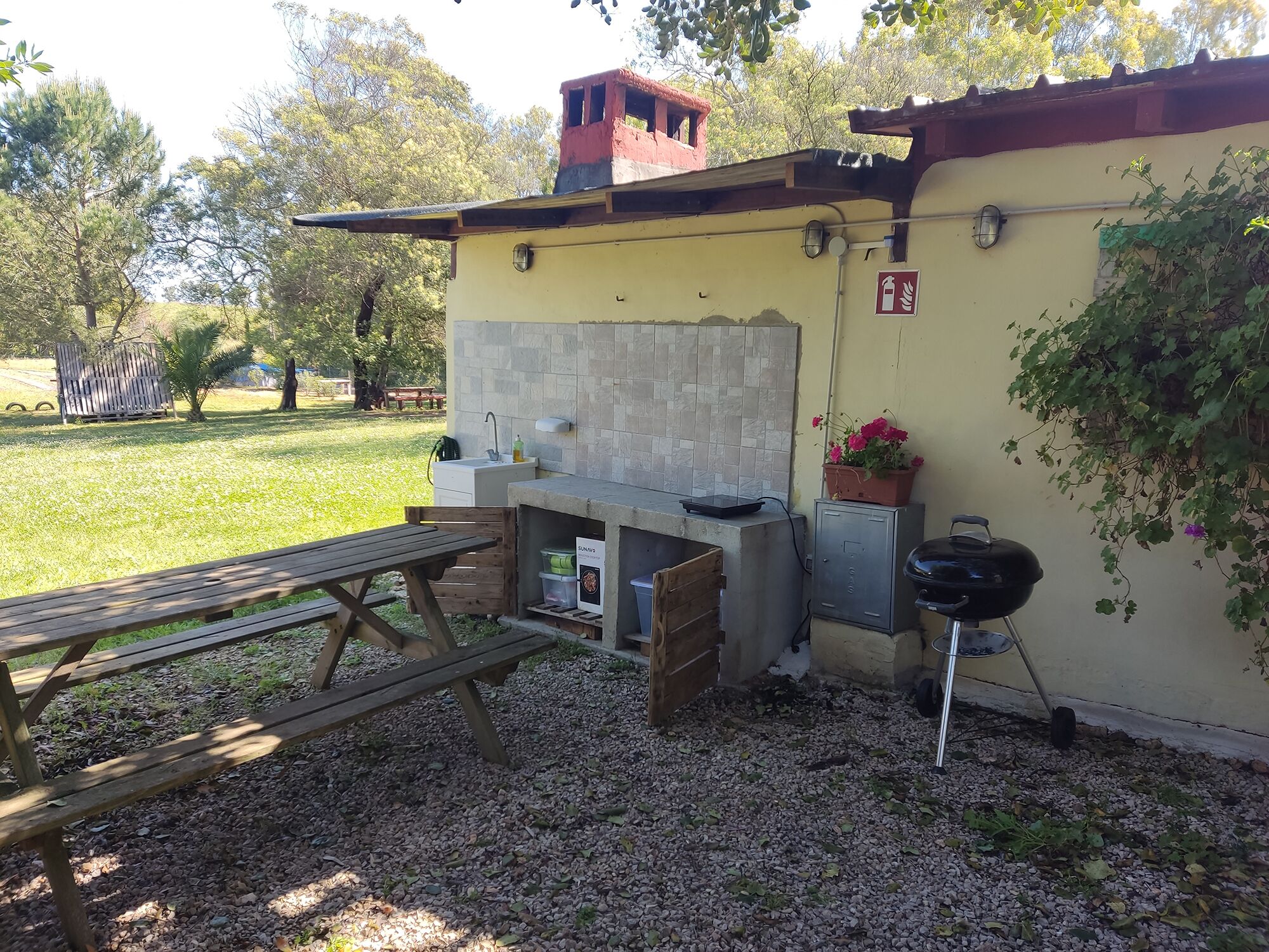 Un espace cuisine extérieur comprenant un barbecue, un évier et une table de pique-nique.