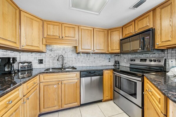 A kitchen with wooden cabinets, a stainless steel dishwasher, a double oven, and a microwave.
