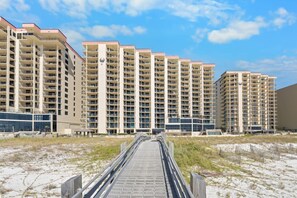 A beachfront hotel with multiple high-rise buildings, a sandy beach in the foreground, and a clear sky.