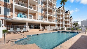 Un hotel con piscina, area salotto all'aperto e diversi balconi.