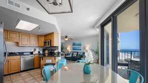 A modern kitchen with wooden cabinets, a dishwasher, and a dining area with a glass table and chairs.