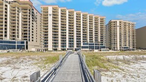 A beachfront hotel with multiple high-rise buildings, a sandy beach in the foreground, and a clear sky.