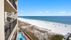 A beachfront hotel with a pool, beach view, and multiple balconies.