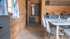 A wooden interior with a dining area, kitchen, and a hallway.