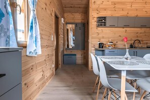 A wooden interior with a dining area, kitchen, and a hallway.