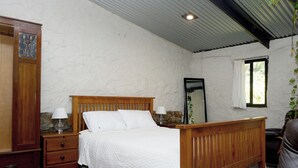 A bedroom with a wooden bed, a nightstand, a dresser, a mirror, and a window with a view of greenery. - The Studio at Meadowbrook: close to the Barossa and Adelaide Hills wine regions. (Kersbrook)