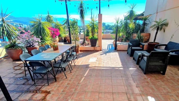 An outdoor patio with a table and chairs, surrounded by potted plants and a view of the sea. - Casa AltaVista  AC Location Terrace Design (Oaxaca de Juárez)